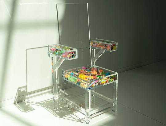 Transparante acrylaatstoel gevuld met speelgoed als kunstobject voor Make-A-Wish