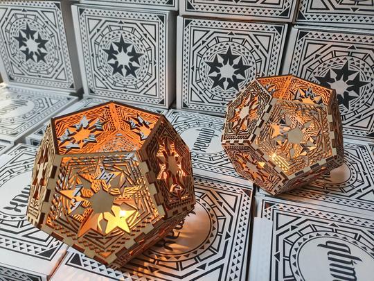 Twee verlichte veelhoekige kaarshouders met geometrische patronen