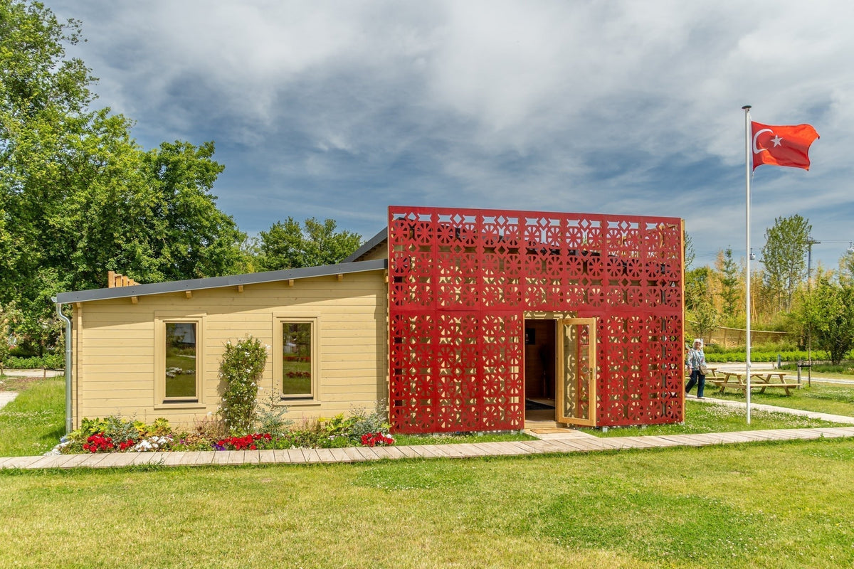 Paviljoen met rode geometrische gevelbekleding en een Turkse vlag