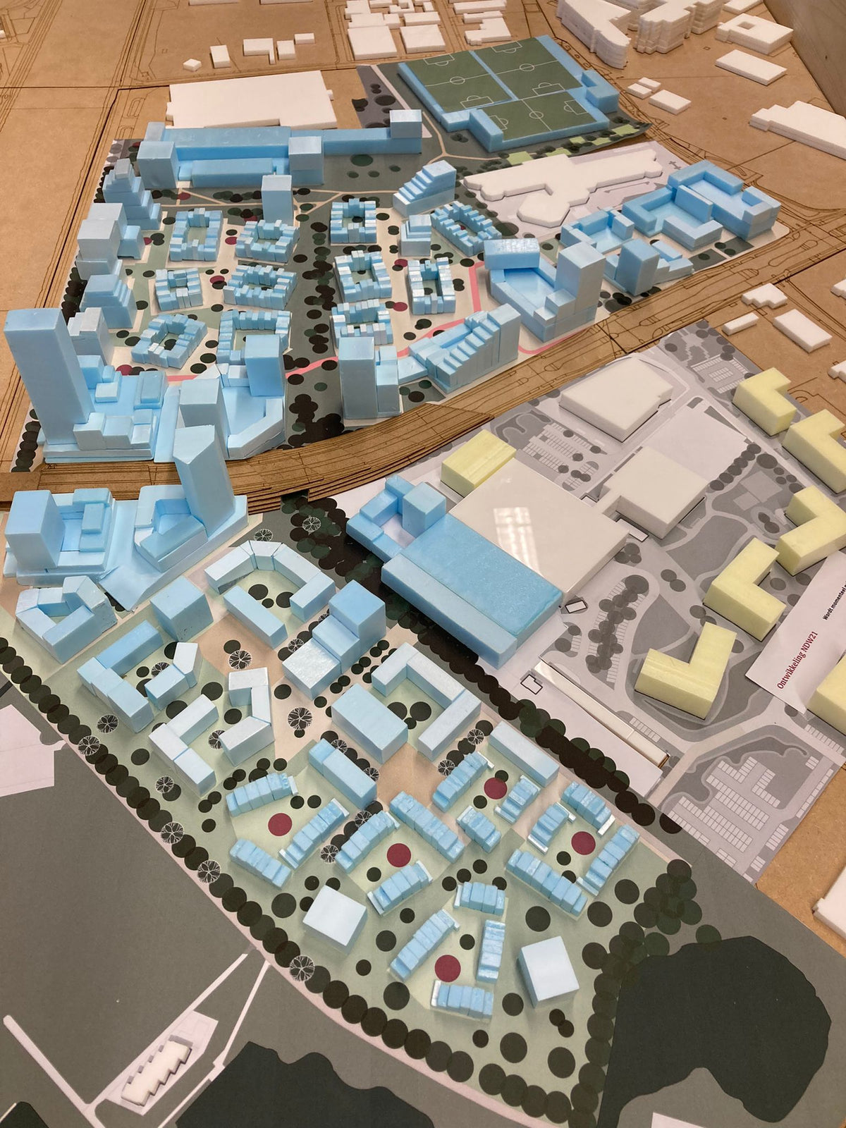 Stedenbouwkundige maquette met blauwe en witte gebouwen, straten en sportvelden