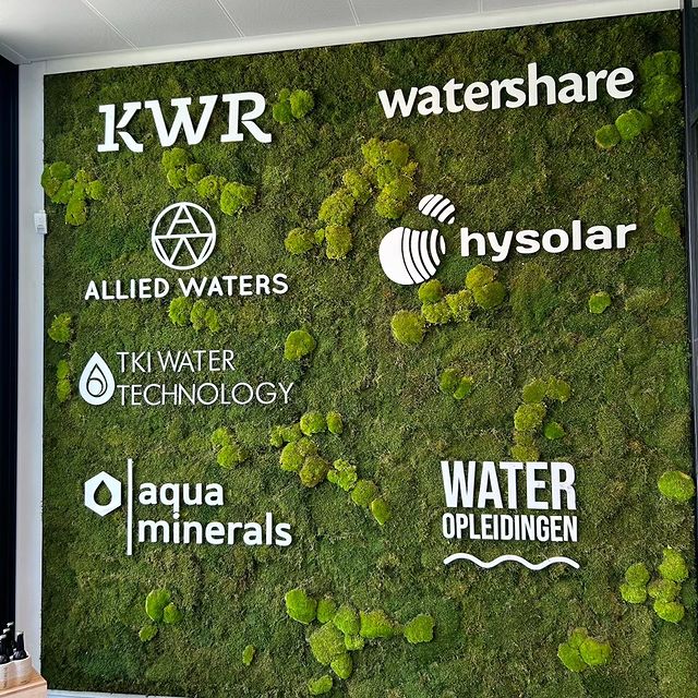 Wit acrylaat logo gemonteerd op een groene moswand